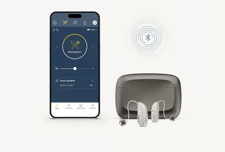 The Jabra Enhance earbuds next to their charging case
